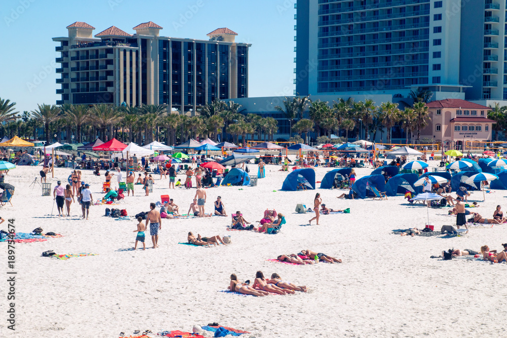Beach holiday destination scene, crowded tropical sandy beach of Clearwater beach Florida, people sun tanning, relaxing and having fun on the beach, holiday hotel resorts on background