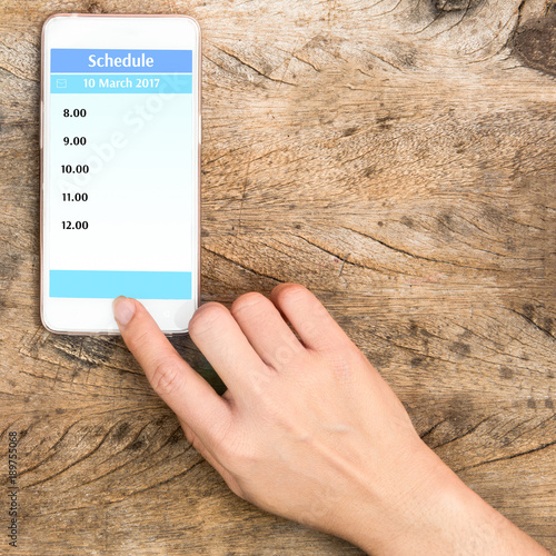 hand pointing home button of smartphone with schadule in screen photo