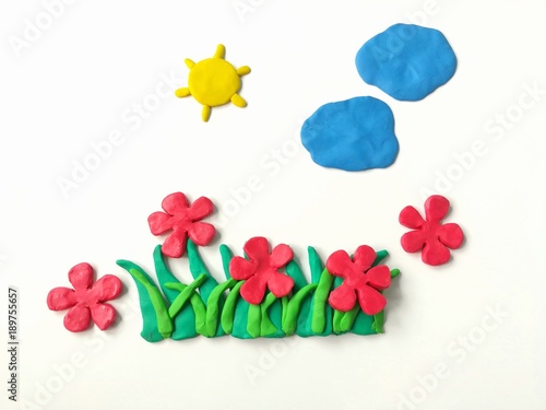 Colorful plasticine clay dough made are red flowers grass sun and clouds on white background, beautiful nature photo