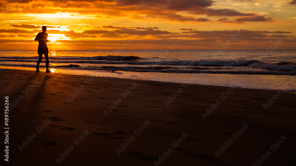 Man is running by the beach at sunrise.