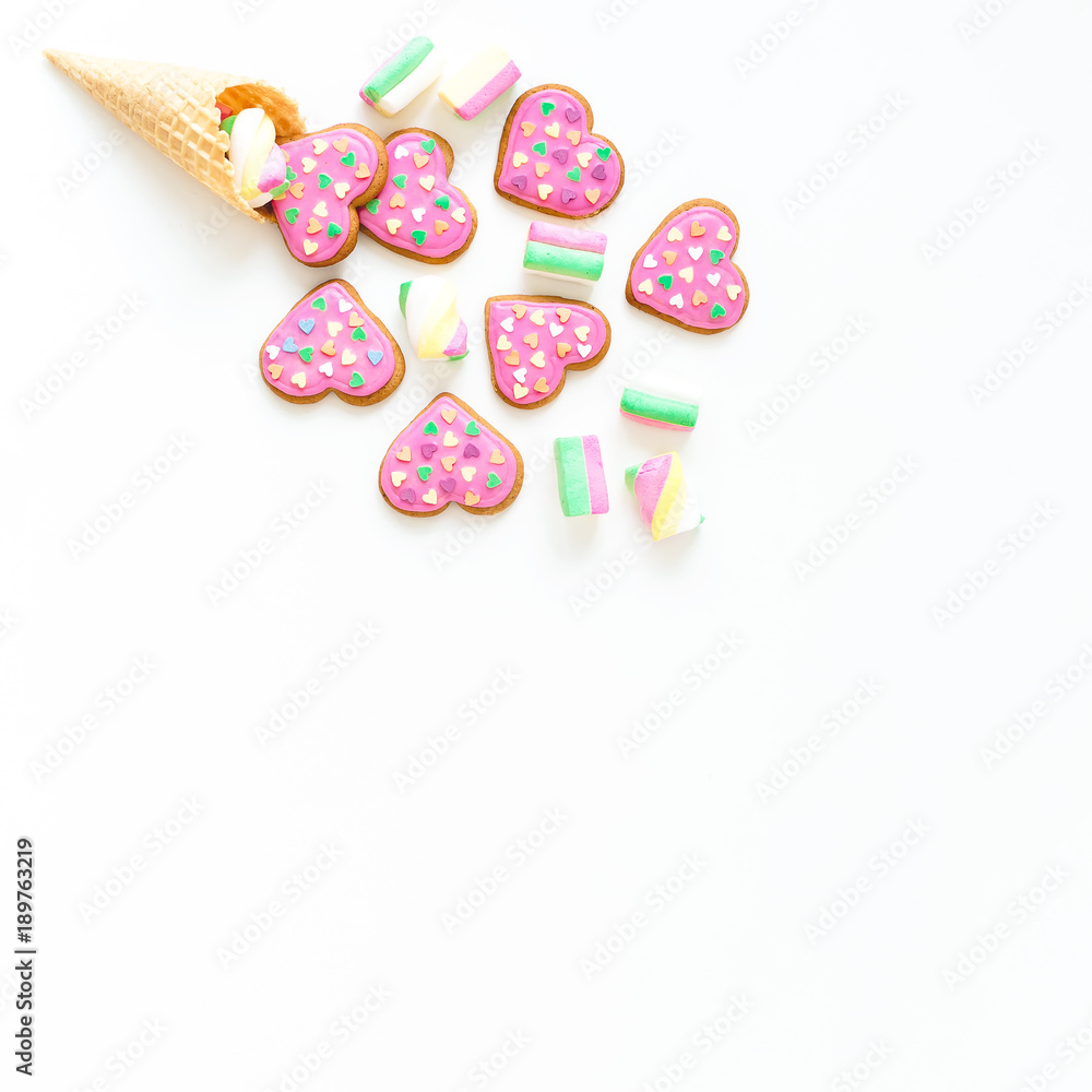 Gingerbread cookies with pink glaze and marshmallow in waffle cone on withe background. Holiday concept. Flat lay. top view. Gingerbread cookies with pink glaze and marshmallow in waffle cone on withe background. Holiday concept. Flat lay. top view.