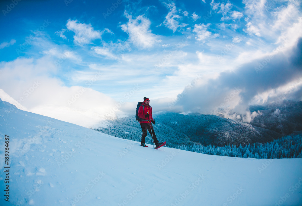 A man in snowshoes in the mountains.