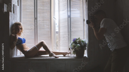 Young blonde model in the blue underwear posing for photographer sitting at the window during fashion photo session © KONSTANTIN SHISHKIN