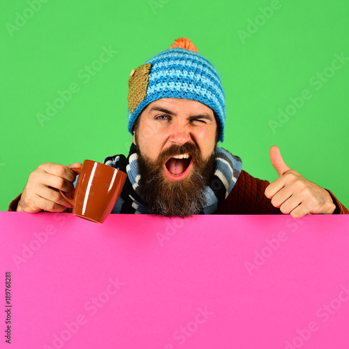 Man holds brown cup on green and pink background