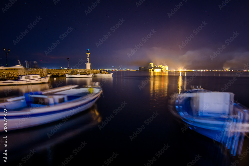 Illuminated old town of Nafplion in Greece with tiled roofs, small port, bourtzi castle, Palamidi fortress at night. Illuminated old town of Nafplion in Greece with tiled roofs, small port, bourtzi castle, Palamidi fortress at night.