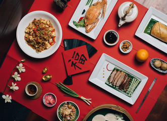 Concept picture for Chinese new year table set up and traditional Chinese dishes on red background with Chinese word means fortune.