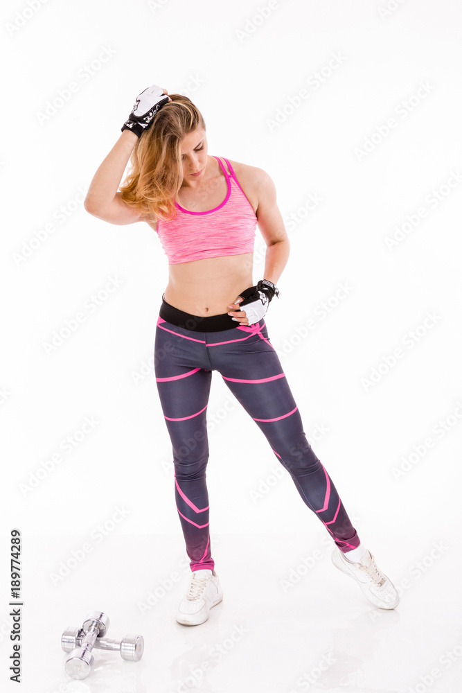 Young Fit Woman Posing on White Background Beside Set of Weights. Sport and Fittness Concept. Young Fit Woman Posing on White Background Beside Set of Weights. Sport and Fittness Concept.
