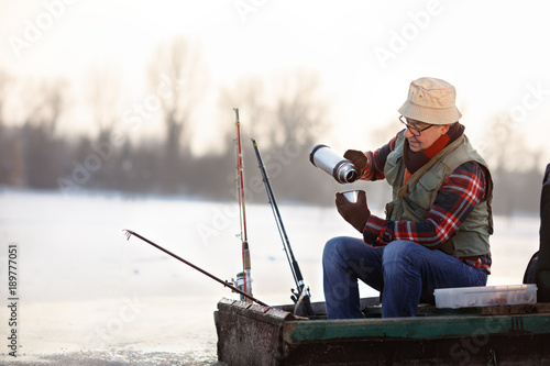 Fisherman taking hot tea while fishing fish