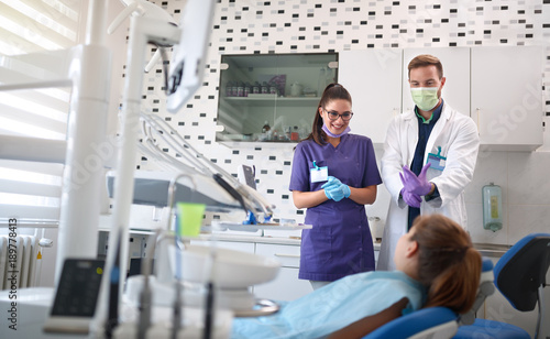 Dentist with assistant talking with patient in dental chair