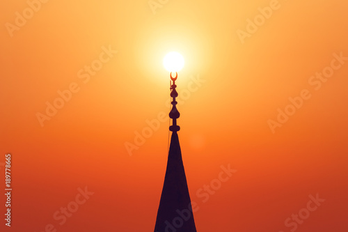Red sunset with sun and silhouette of mosque minaret