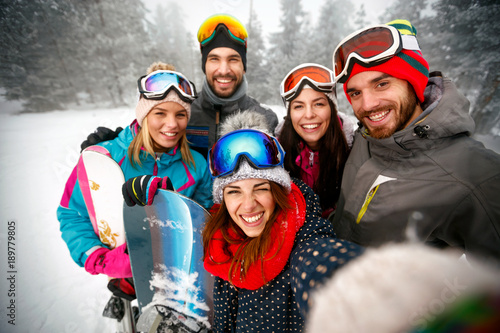 Group of smiling friends having fun Snowboarders and skiers making selfie