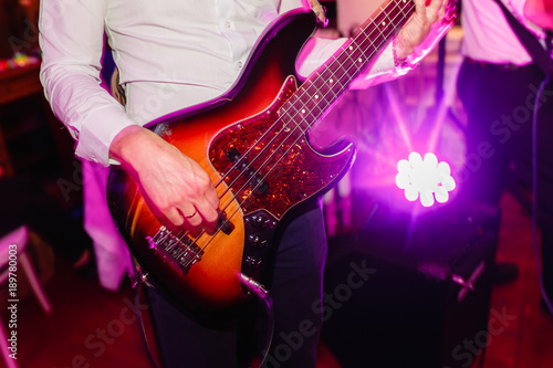 Guitarist plays the guitar in the club close-up of hands. Guitarist plays acoustic guitar in night club, blue lights, close up