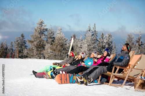 friends skiers relax in chairs on the mountain top