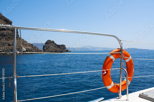 Orange safety flotation device on the side of a boat with the ocean in the background