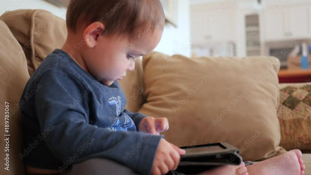 Adorable boy toddler playing with his ipad on couch Adorable boy toddler playing with his ipad on couch