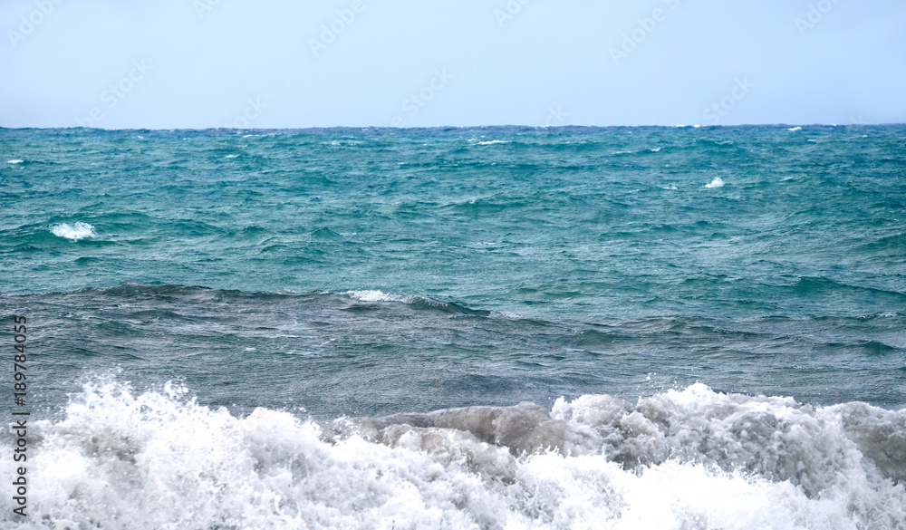 Landscape with sea waves splashes of white foam fly upward on windy summer day