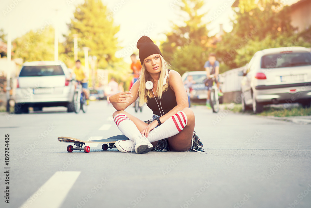 Cool skater girl in street style, sitting on the street posing with skate  board in urban environment Stock 写真 | Adobe Stock