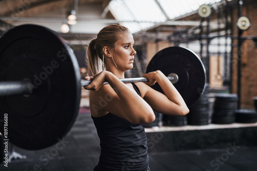 Focused young woman lifting heavy weights alone in a gym