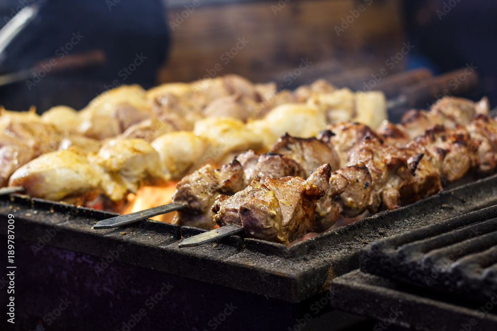 The process of cooking shish kebab on a metal grill in the open air.Grilling shashlik on barbecue grill. Marinated meat. The process of cooking shish kebab on a metal grill in the open air.Grilling shashlik on barbecue grill. Marinated meat.
