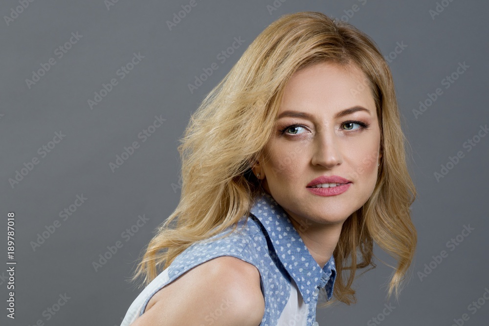 Close-up studio portrait of a beautiful middle aged blonde woman. Gray background Close-up studio portrait of a beautiful middle aged blonde woman. Gray background