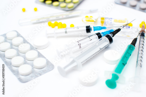 Syringes and pills different as the background on a white background