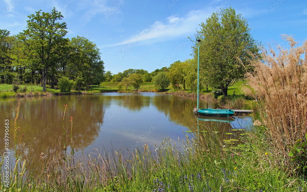 Peaceful pond with a small boat at dock, France Peaceful pond with a small boat at dock, France