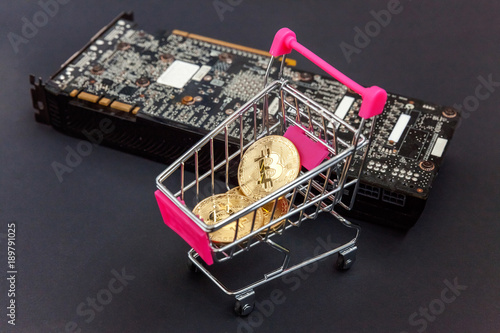 Stack of coins bitcoin in mini shopping cart toy on the video card, concept of mining. Electronic virtual money for web banking and international network payment. Symbol of crypto currency photo