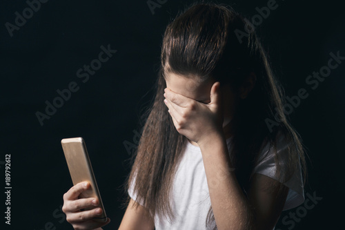 young sad vulnerable girl using mobile phone scared and desperate suffering online abuse cyberbullying being stalked