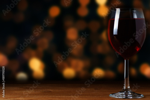 A glass of red wine on a background of blurred garlands