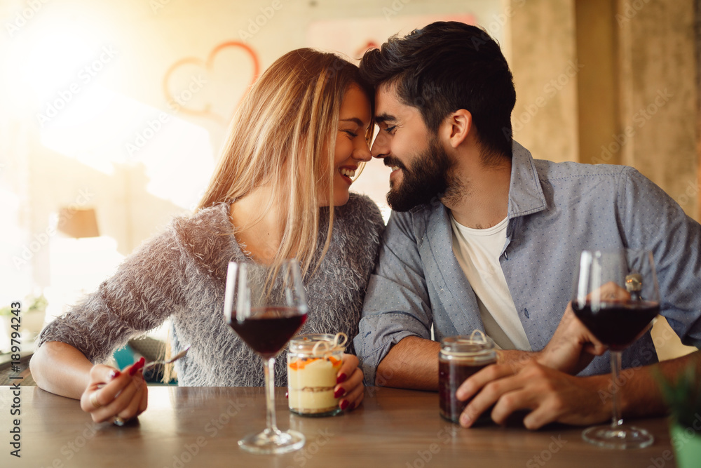 Couple in love having romantic moments in cafe. Couple drinking wine and celebrating Valentine's day. Couple in love having romantic moments in cafe. Couple drinking wine and celebrating Valentine's day.