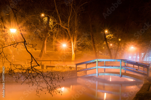 фотографія Beautiful night scene with a wooden bridge over the lake illuminated by lights i