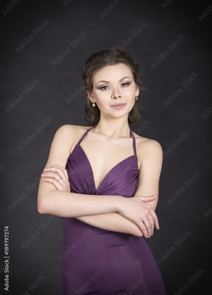 A young,smiling girl in dress posing on a dark background. A young,smiling girl in dress posing on a dark background.