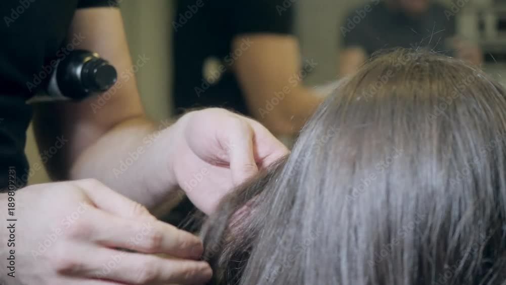 Closeup hairdresser man makes hairstyle for young woman in beauty salon Closeup hairdresser man makes hairstyle for young woman in beauty salon