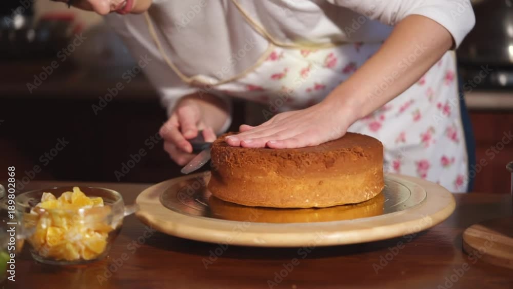 close up shot of a woman's hands, the cook cuts with a knife a freshly baked cake into small pieces, a flour dessert stands on a wooden stand on the table close up shot of a woman's hands, the cook cuts with a knife a freshly baked cake into small pieces, a flour dessert stands on a wooden stand on the table