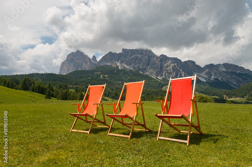 Three colorful deck chairs in front of beautiful Tofane mountain group