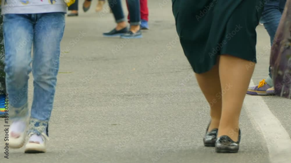 The feet of people are walking along the street The feet of people are walking along the street