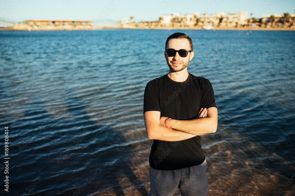 Fototapeta premium Young handsome man wearing spectacles and having fun on sea beach