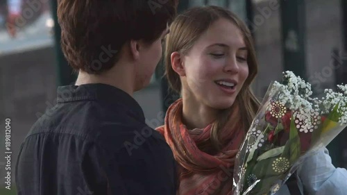 Happy young man and woman holding flowers