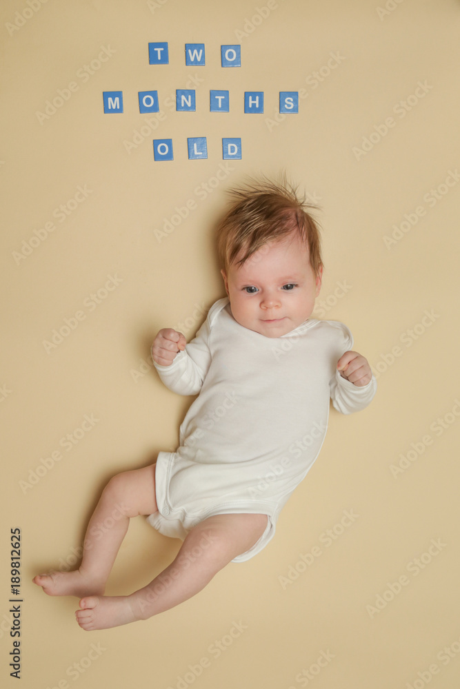 Adorable two months old baby on the yellow background, studio shot Adorable two months old baby on the yellow background, studio shot