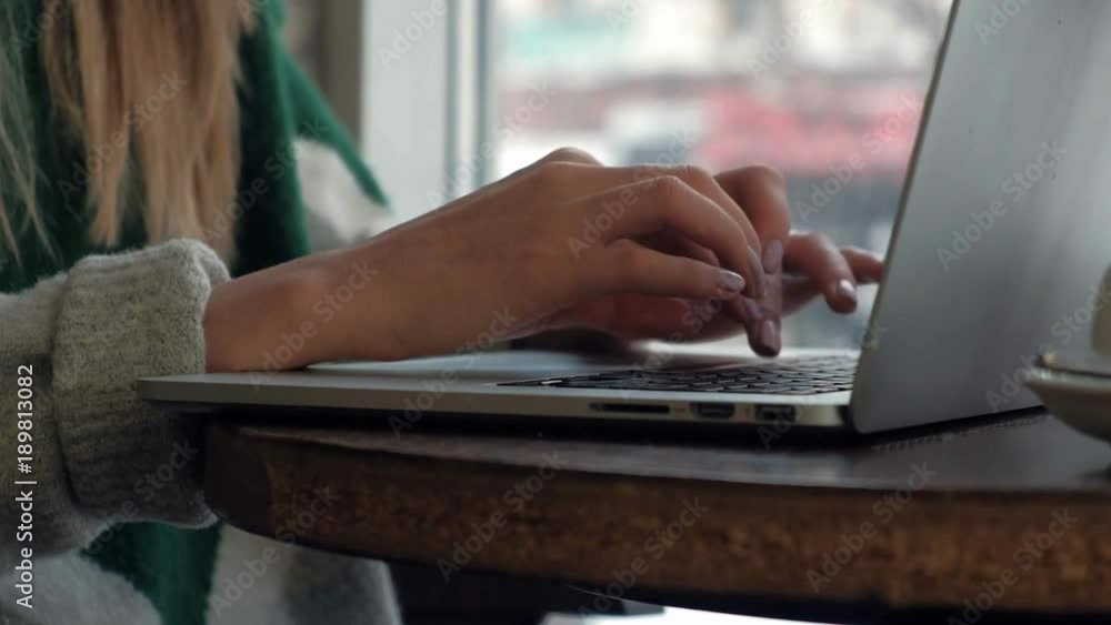 Beautiful girl model sitting at a table in a cafe and working on the computer Beautiful girl model sitting at a table in a cafe and working on the computer
