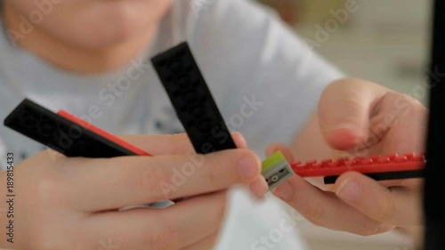 Child's hands playing with a construction toy set, smart kid, plastic bricks