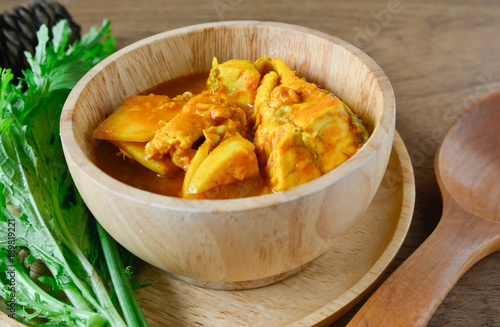 Thai food Curry yellow soup of fish and baby coconut meat serve in wooden bowl and vegetable.