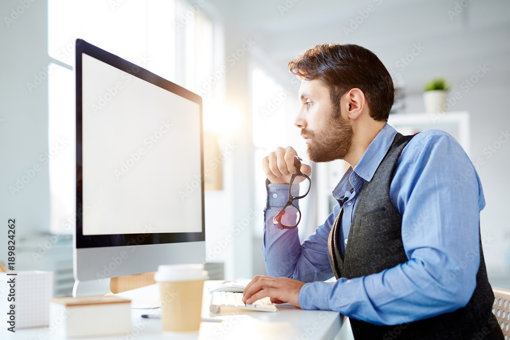 Fototapeta premium Modern manager or designer concentrating on reading online information on monitor display