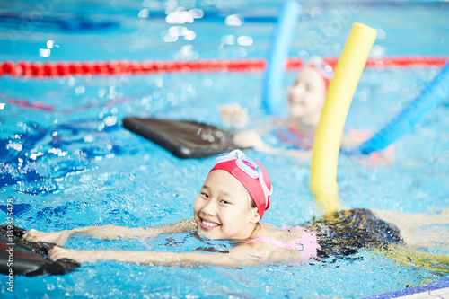 Cute girl having fun while learning to swim with special resistance inflatable equipment