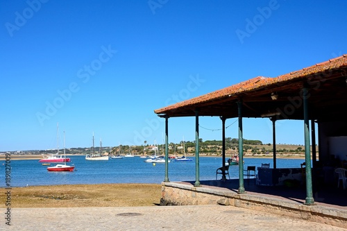 Yachts moored in the estuary with the fish market building to the right hand side in the foreground  Algarve  Portugal.