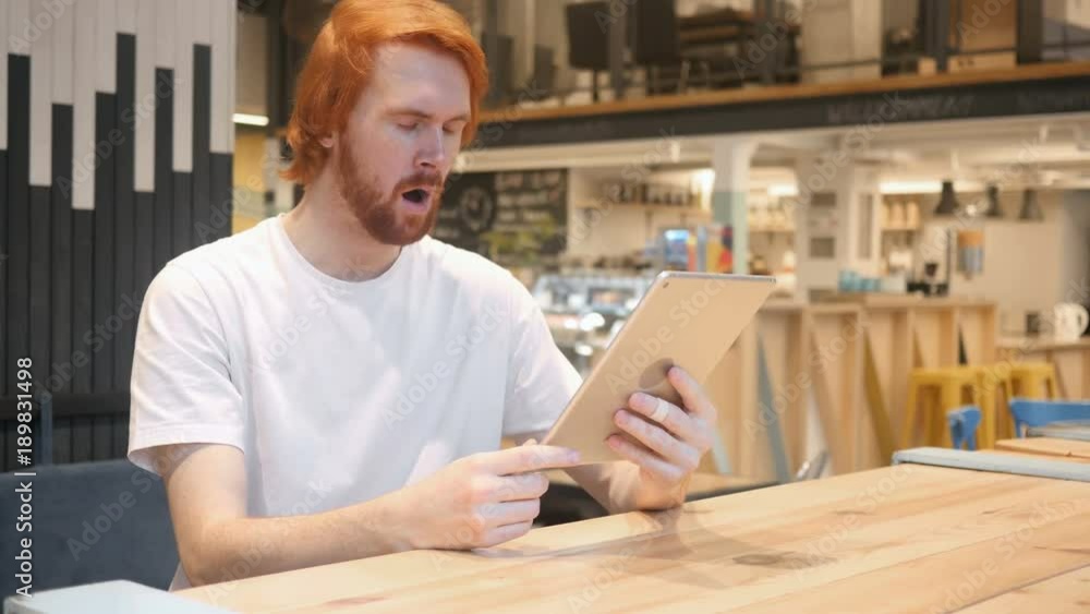 Redhead Beard Man In Shock, Reading Email on Tablet PC in Cafe Redhead Beard Man In Shock, Reading Email on Tablet PC in Cafe