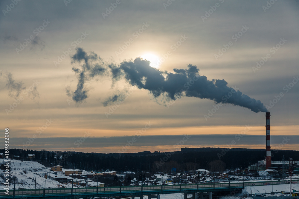 An industrial view of a sunrise in the city. Rolling hills is crossed by a highway and accompanied by a Heating plant with a white and red striped pipe. An industrial view of a sunrise in the city. Rolling hills is crossed by a highway and accompanied by a Heating plant with a white and red striped pipe.