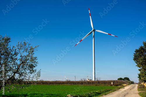 Horizontal View of an Eolic Wing in an Italian Countryside in a Green Meadow on Blue Sky Background