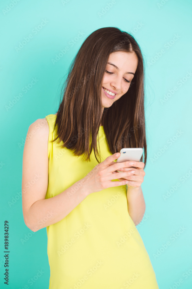 Girl in a yellow dress holding smartphone with blue backround