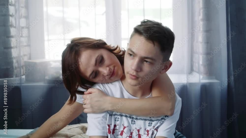 A cute woman is sitting in an embrace with her teenage son. A cute woman is sitting in an embrace with her teenage son.